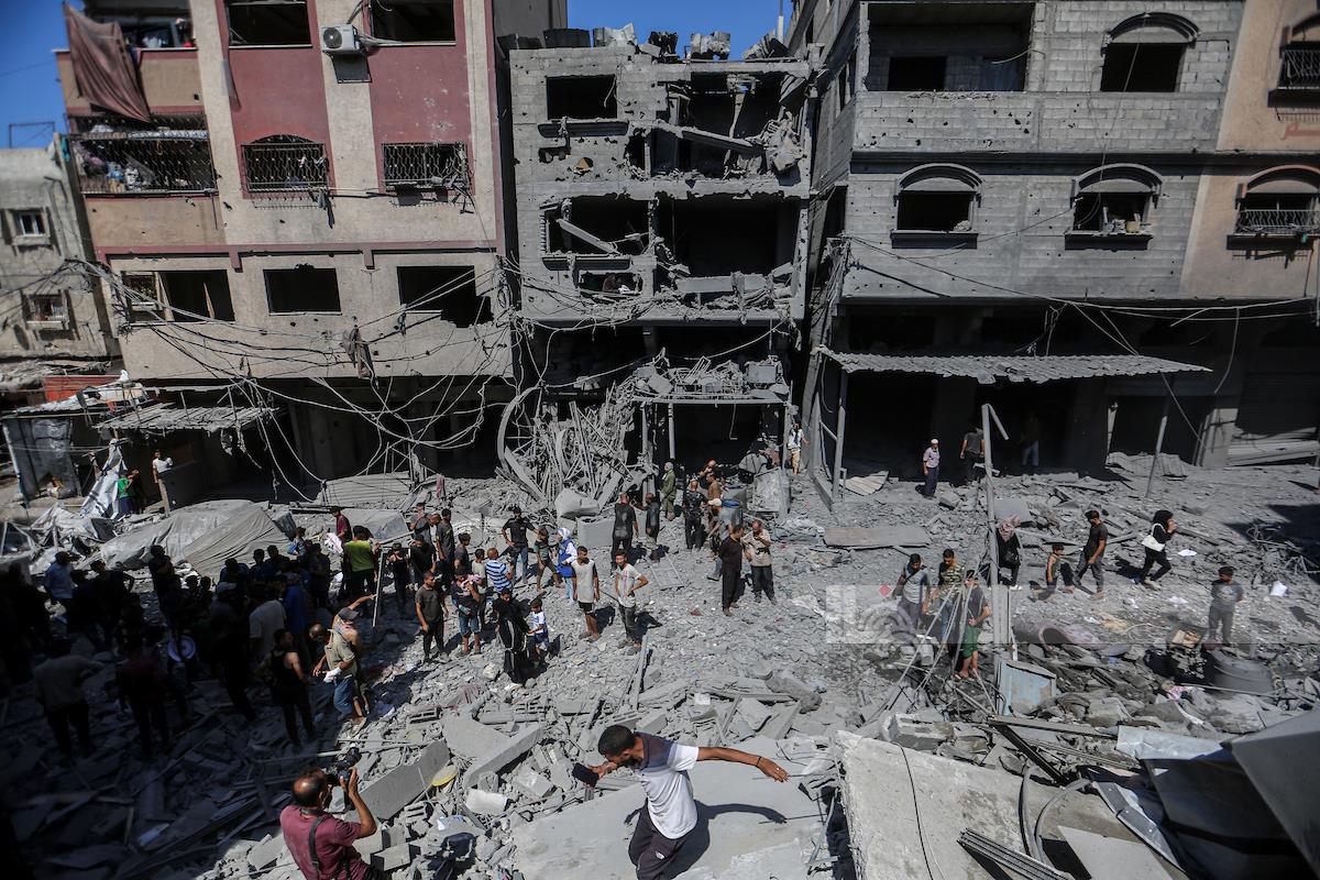 مواطنون يتفقدون الدمار الذي لحق بمنزل يعود لعائلة حمودة في مخيم الشاطئ بعد أن قصفته طائرات الاحتلال الإسرائيلي (وفا)